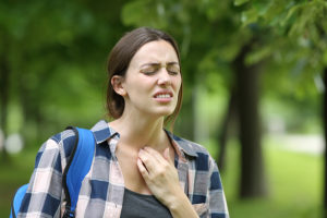 Stressed female student suffering a sore throat while walking on college campus